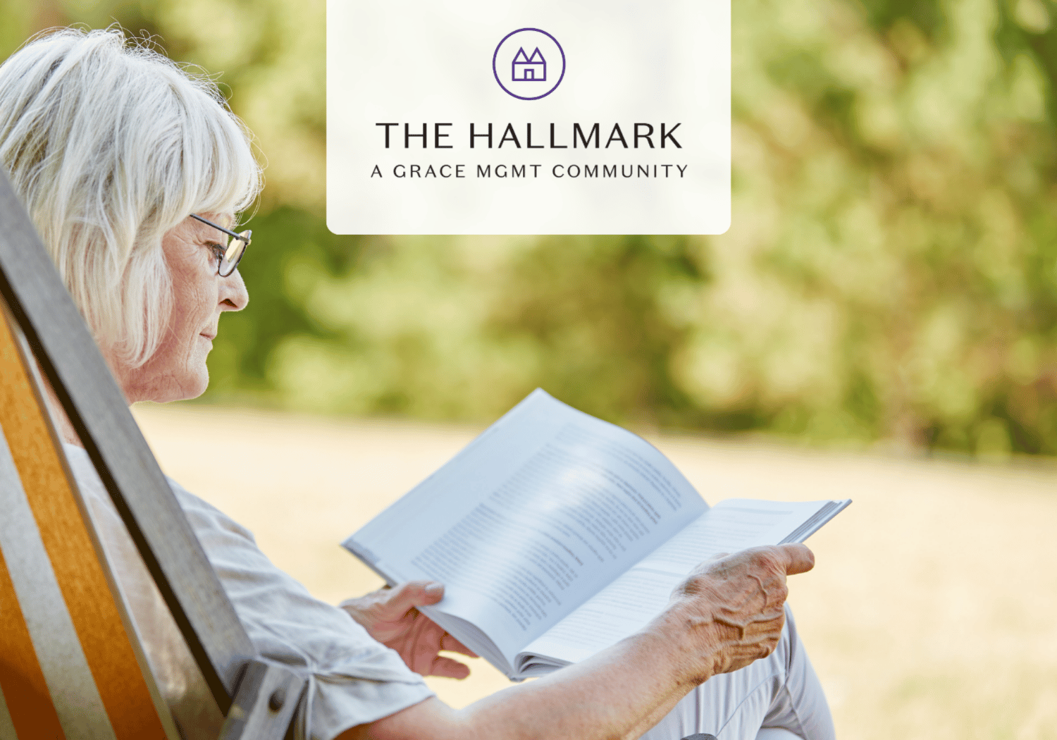 Older woman reading a book outdoors in a chair, with a circular logo and text 'THE HALLMARK A GRACE MGMT COMMUNITY' at the top.